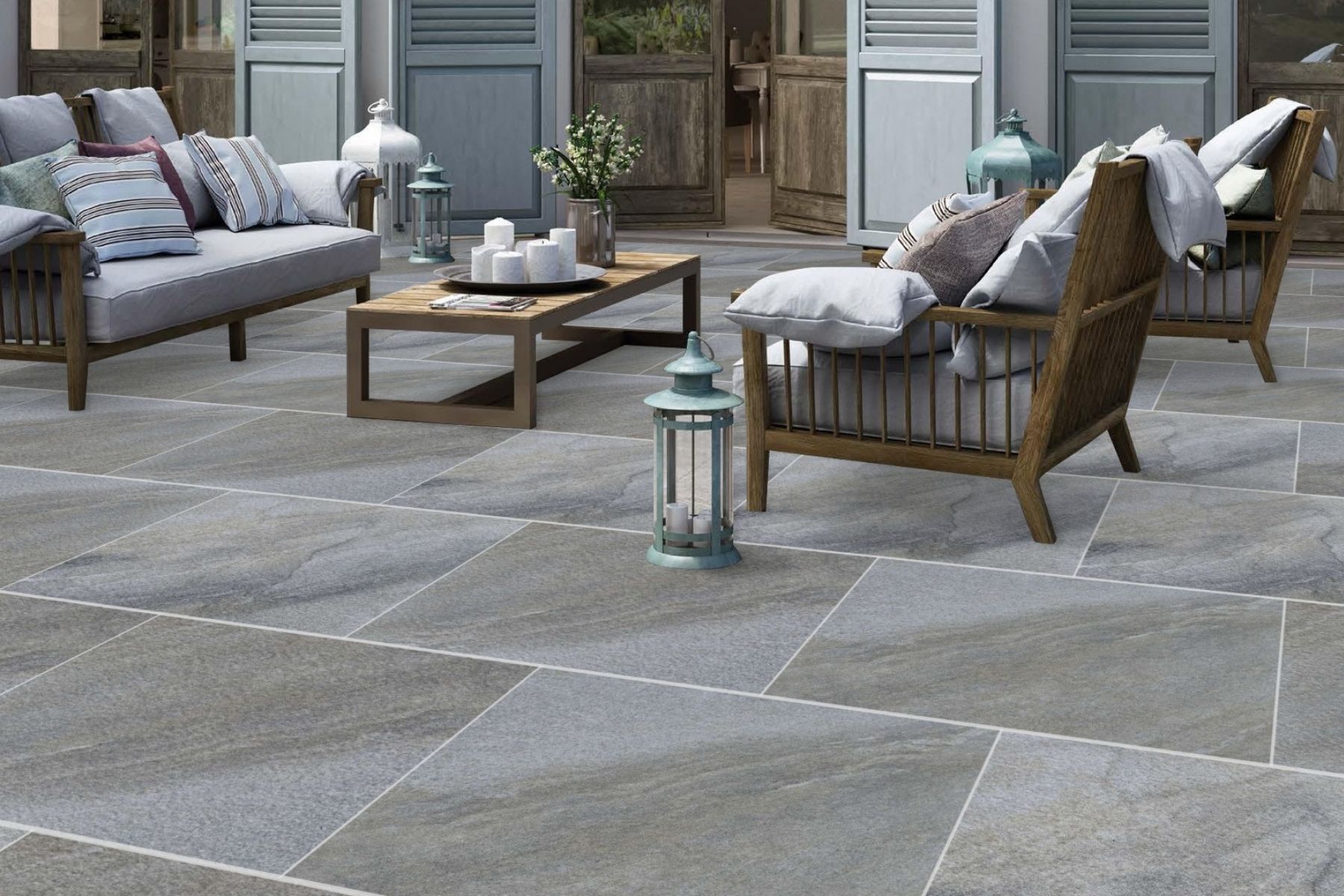 outdoor porcelain pavers in 20mm with a light grey wave look laid in brick pattern with grout on top is a wooden outdoor set